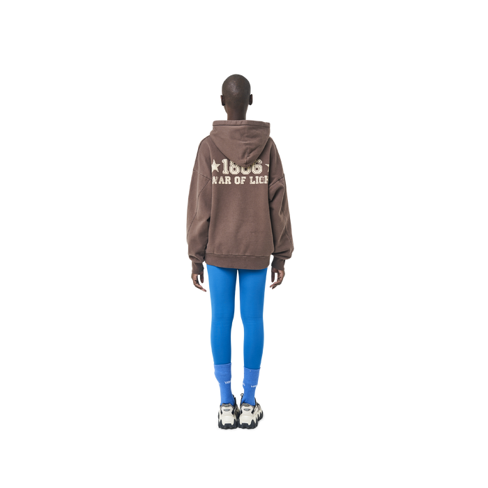 Long sleeves oversize cut hoodie in washed brown color fabric featuring 1886 print at back. 1886 logo embroidered at kangaroo pocket. A button on the hood. Rib knit at cuffs and hem