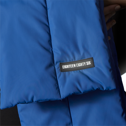 Rectangular down puffer scarf in blue featuring Eighteen Eighty-Six logo patch sewn at bottom.